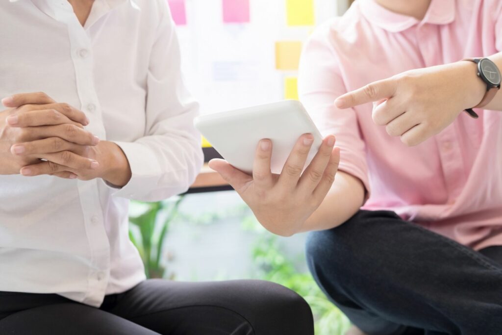 Duas pessoas conversando segurando um tablet e apontando para o mesmo