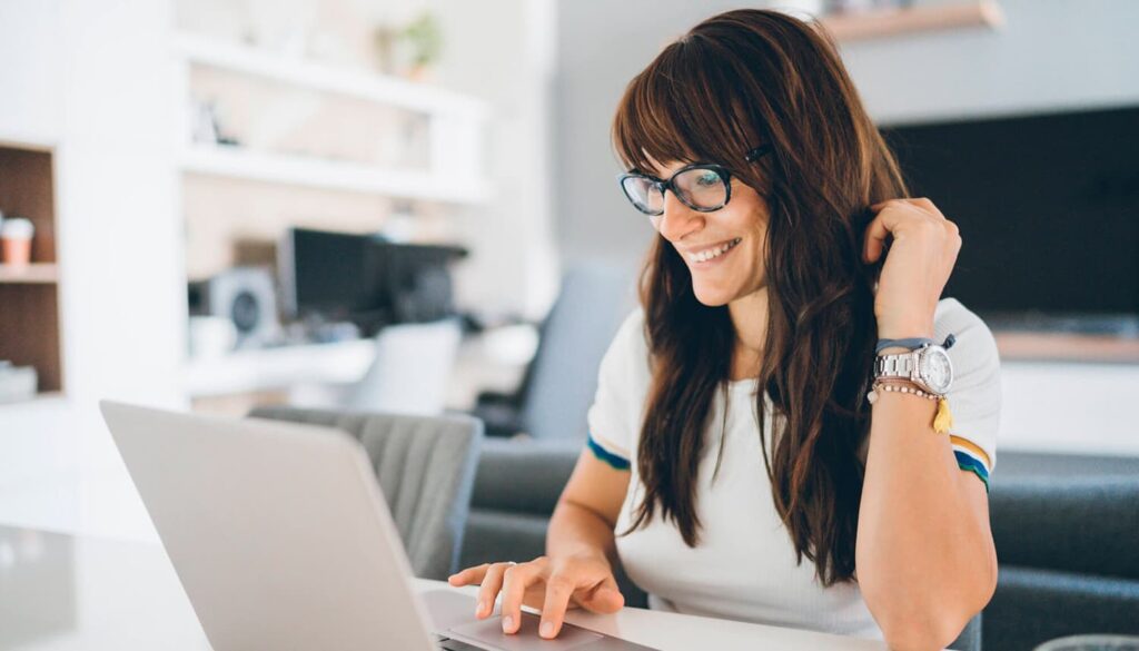 Mulher usando um notebook, em uma mesa.