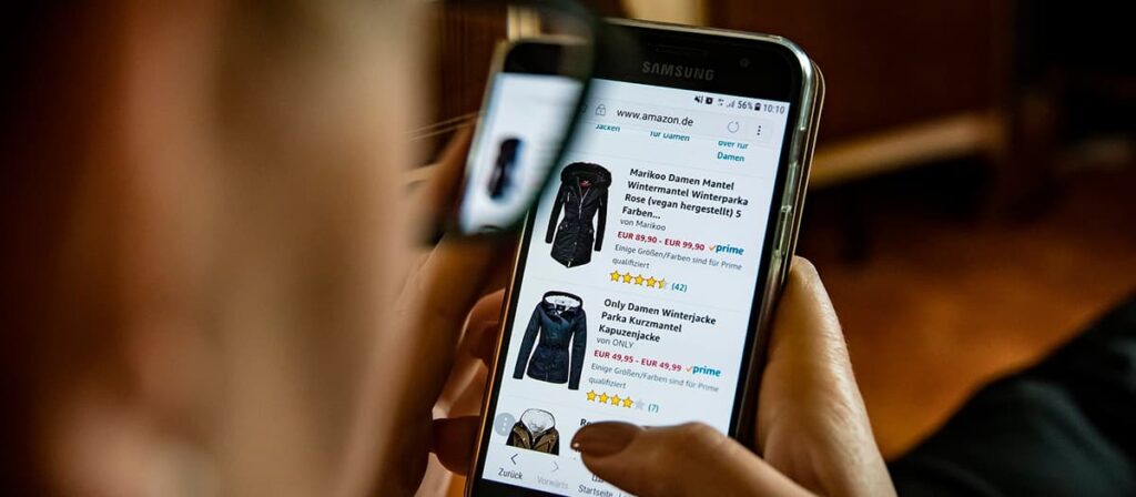 Mulher pesquisando roupas em site, no celular.