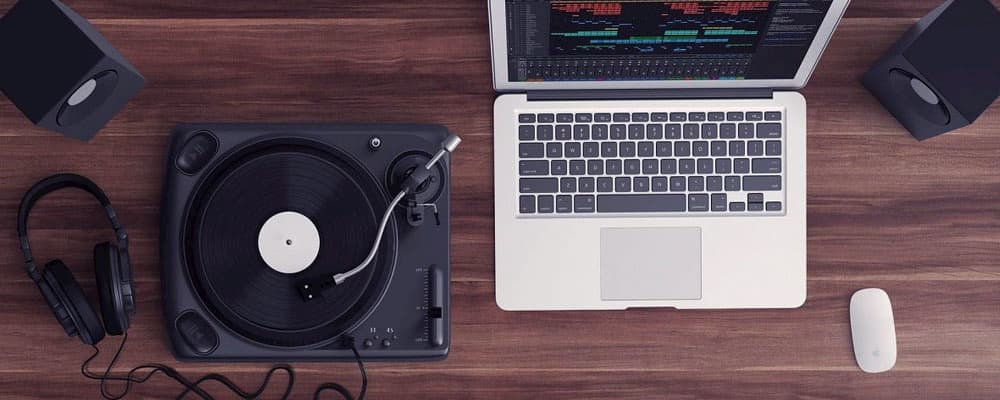 Uma mesa com uma vitrola, um fone de ouvido e um notebook